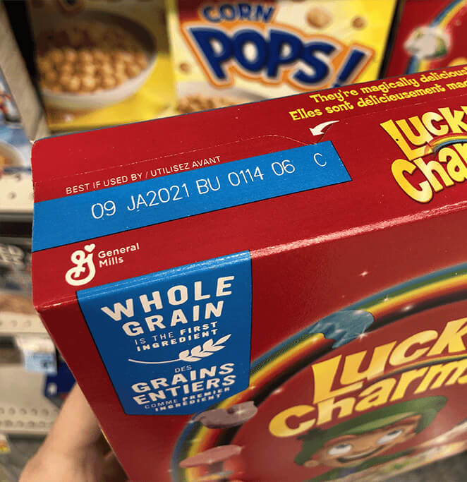 The top of a Lucky Charms box, showing how the expiration date is stamped imprecisely onto a large blue rectangle