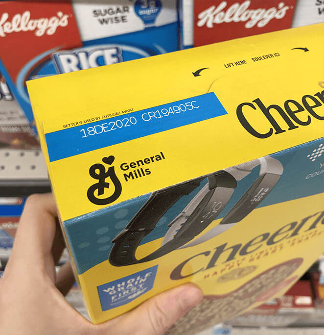 The top of a Cheerios box, matching the Lucky Charms box with a blue rectangle and stamped expiration date